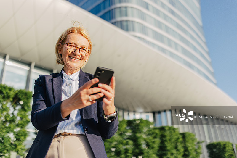 快乐的女人在户外用智能手机自拍图片素材