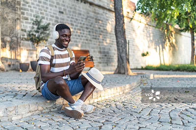 游客戴着耳机听音乐并浏览智能手机图片素材