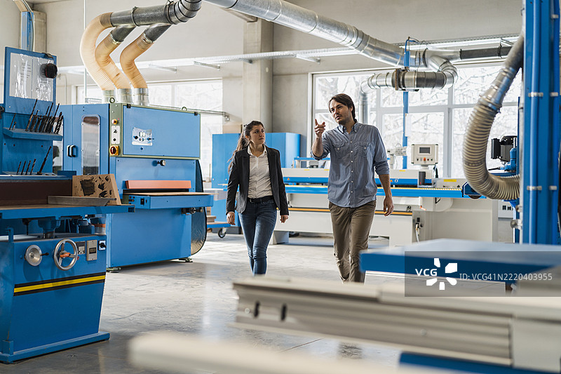 专家在工业区向女商人展示机械设备。图片素材