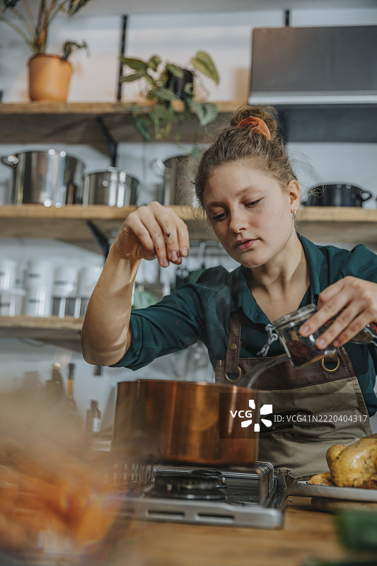 在厨房中，专家在铜锅中添加调味料以烹饪高汤图片素材