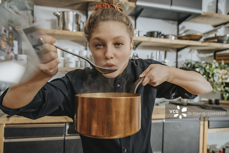 年轻厨师在厨房里品尝汤汁图片素材
