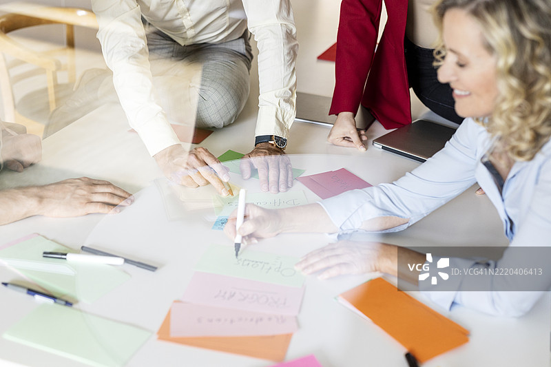 微笑的女商人正在开放式办公室的桌子旁向同事们解释项目图片素材