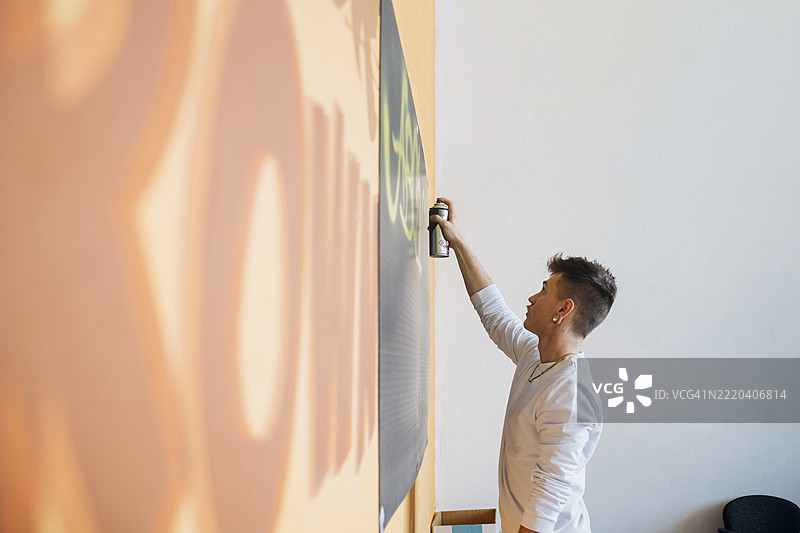 时髦男子在工作室里向黑板喷涂油漆图片素材