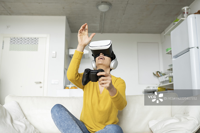 成熟的女性在家中佩戴虚拟现实头盔并做手势图片素材