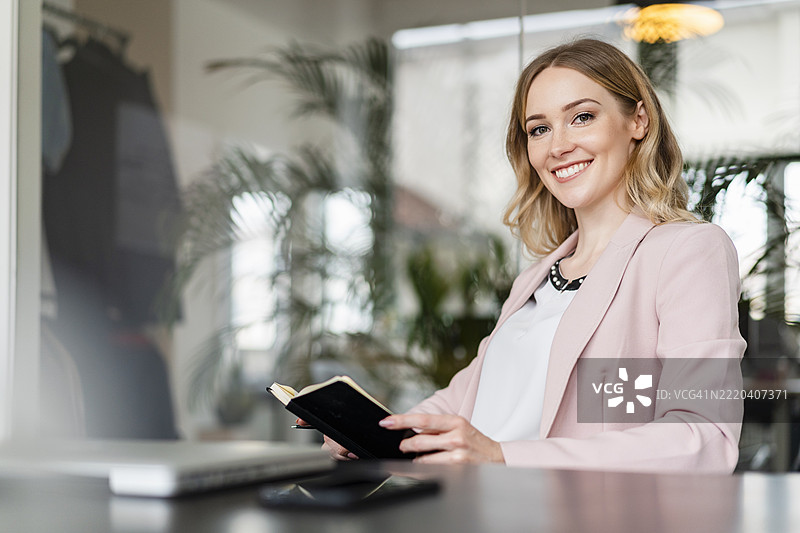 女商人在办公室的桌子上拿着日记本图片素材