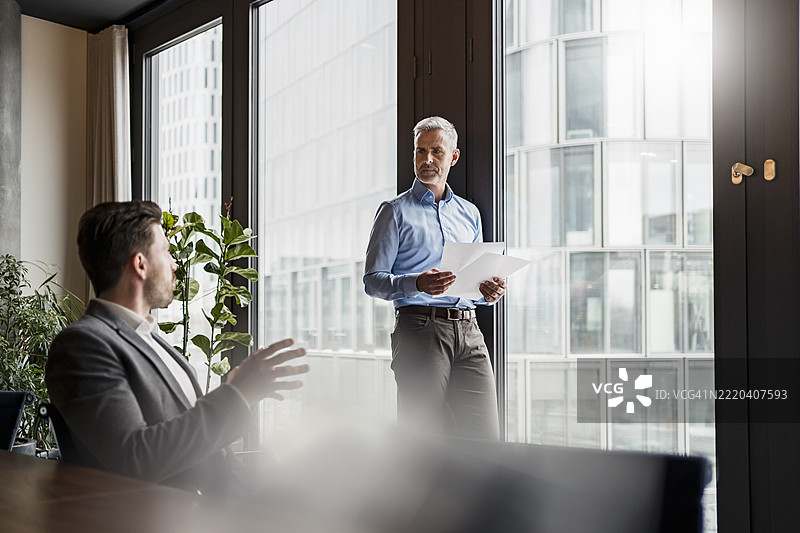 男性专业人士在办公室讨论战略文件图片素材