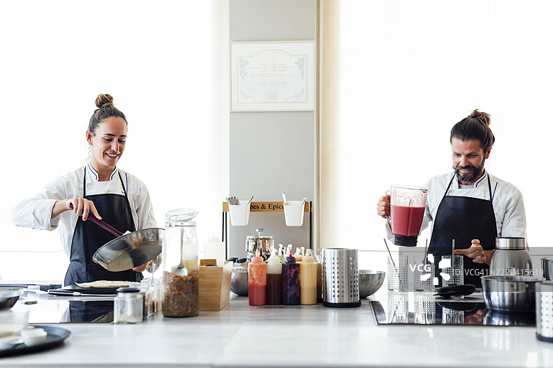 男女厨师在现代餐厅的厨房里准备食物图片素材