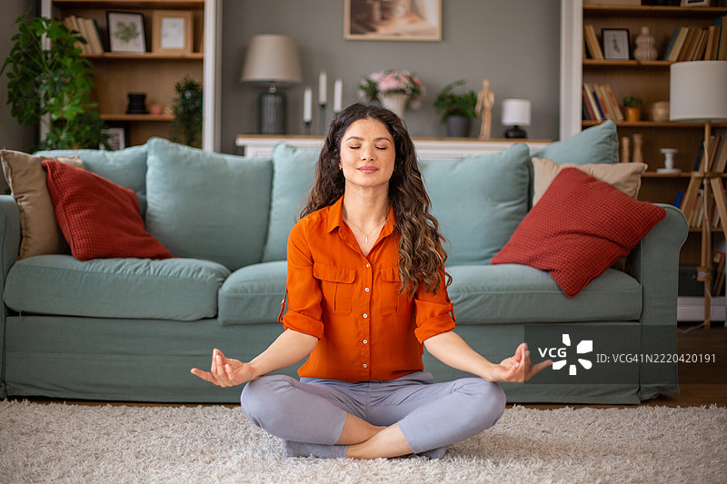 年轻女性在家中地毯上以莲花坐姿冥想图片素材
