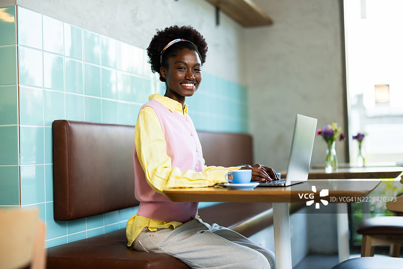年轻的黑人女性自由职业者在咖啡店使用笔记本电脑工作图片素材