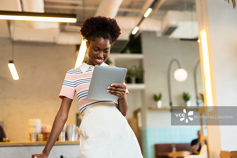 微笑的女服务员在咖啡馆使用平板电脑管理订单图片素材