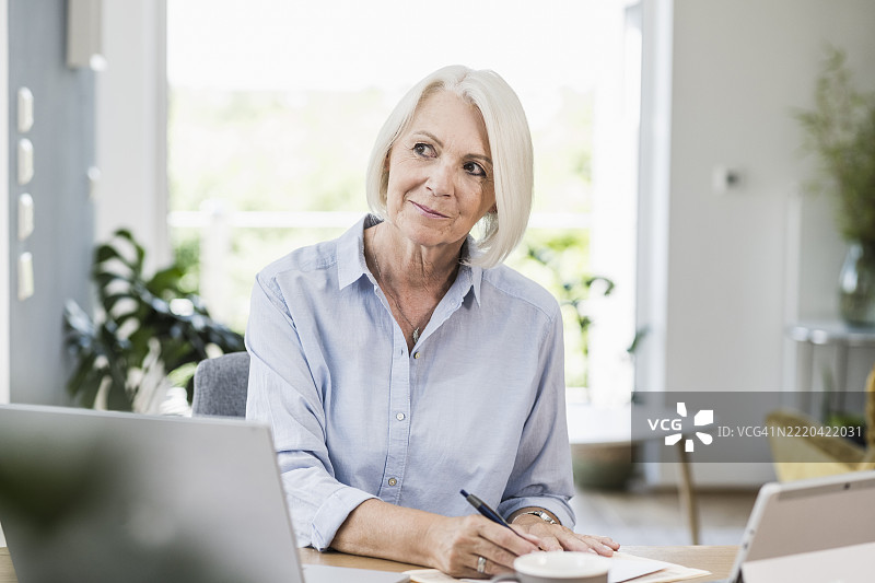 深思的女性专业人士在家办公时望向一旁图片素材