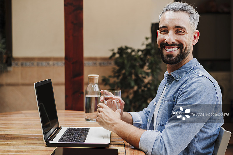 中年男商人在桌子旁喝水图片素材