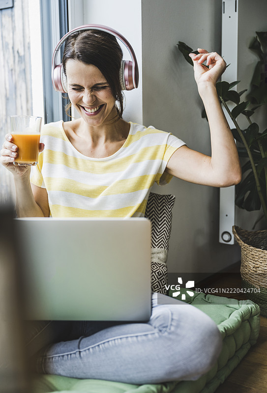 在家听音乐时，女人做手势。图片素材