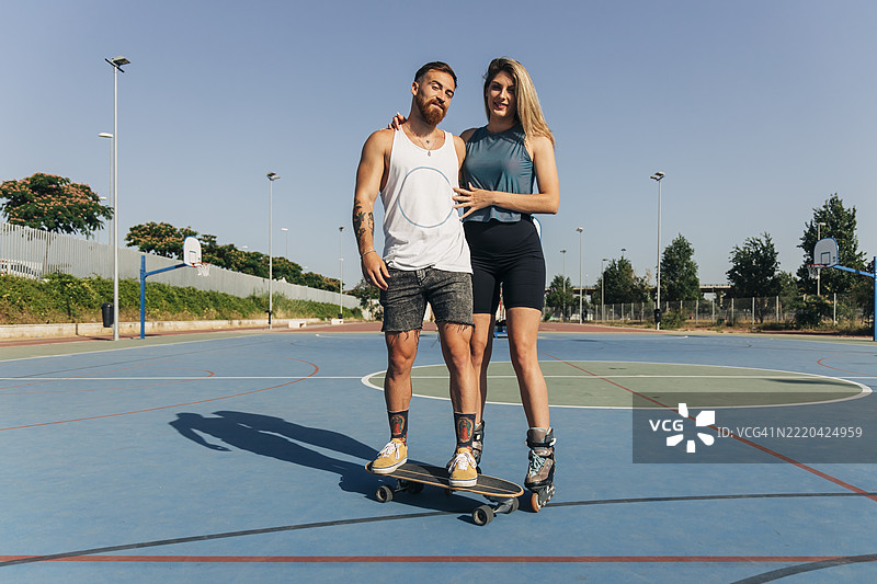 阳光明媚的日子里，年轻女子与男友在篮球场上。图片素材