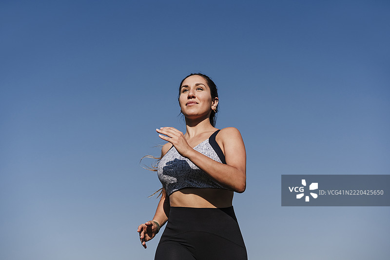 年轻坚定的女运动员在日落时分慢跑图片素材