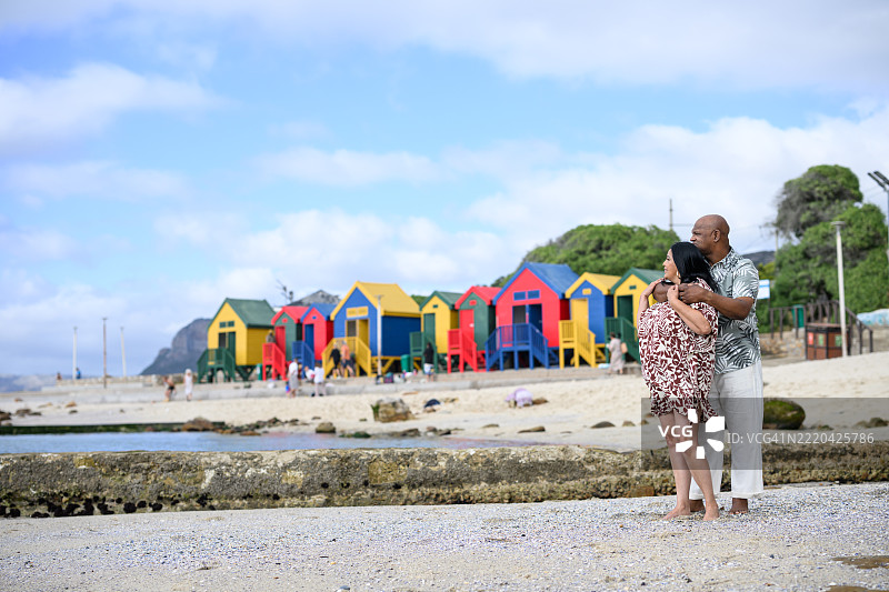 成熟夫妇在穆伊岑堡海滩的广角镜头，享受着浪漫假期，背景是五彩斑斓的房屋。图片素材