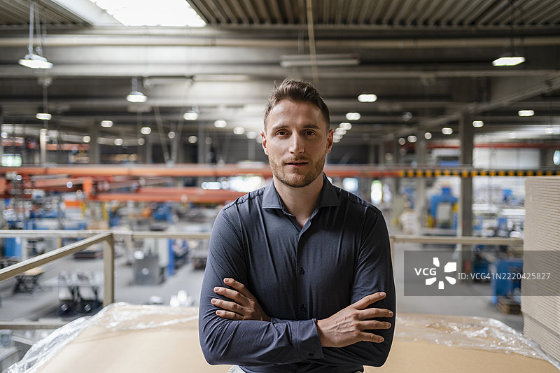 男性专业人士双臂交叉站立在工业环境中图片素材