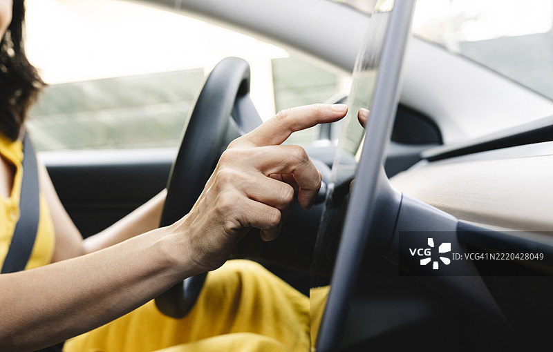 成熟的女性在电动车中使用平板电脑图片素材