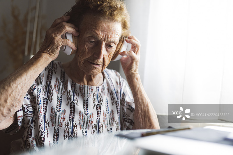在家中戴着耳机的老年女性图片素材