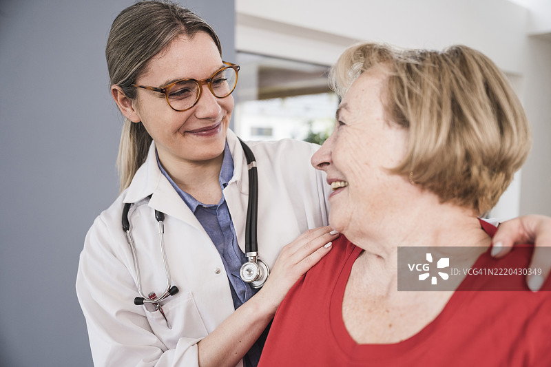 微笑的医生在家中双手搭在病人肩膀上图片素材