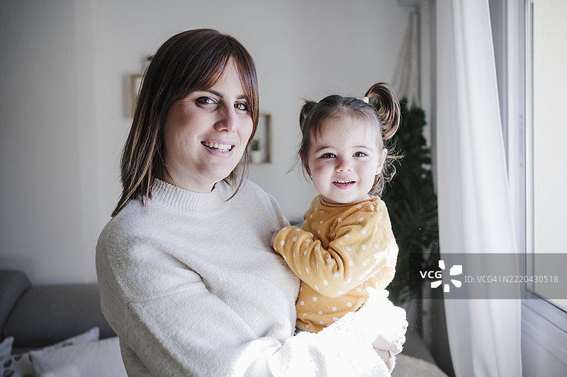 微笑的母亲在家中抱着女婴图片素材