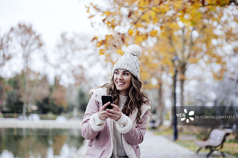 快乐的女人在公园里拿着手机图片素材