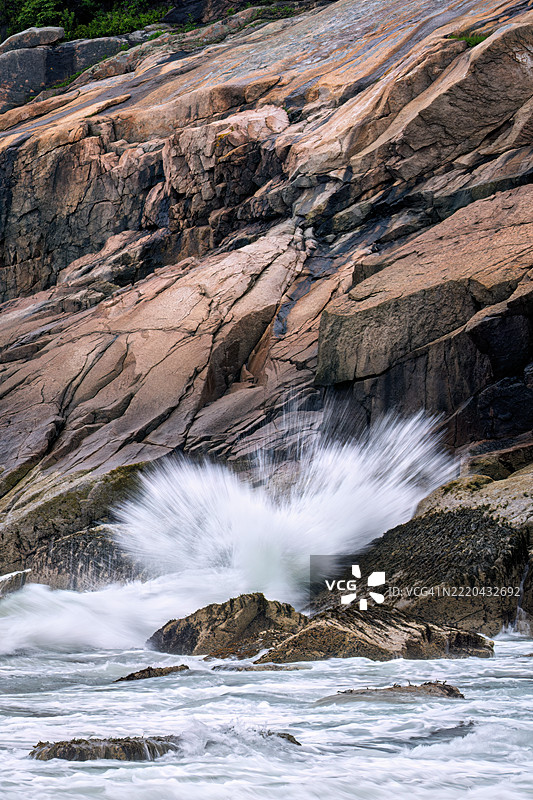 在缅因州阿卡迪亚国家公园的沙滩上，雾蒙蒙的早晨，长时间曝光捕捉到海浪拍打海岸的景象。图片素材