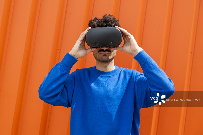 戴着VR眼镜的男子，背景为橙色图片素材