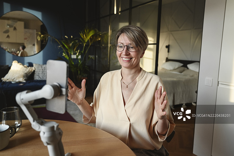 微笑的女性在家中使用手机稳定器拍摄图片素材