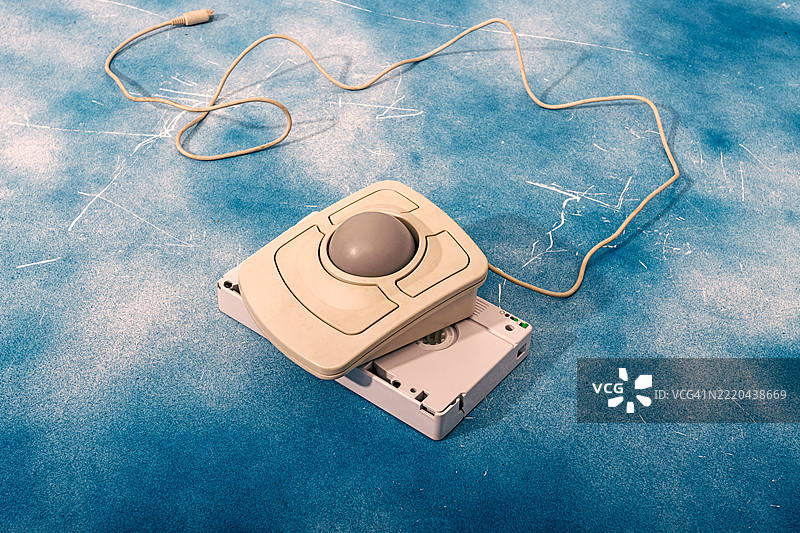 复古轨迹球鼠标与蓝色背景的VHS录像带图片素材