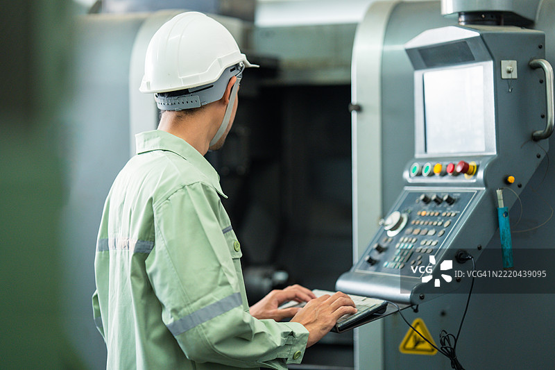 匿名工厂工人或工程师从背后编程计算机数控（CNC）机床图片素材