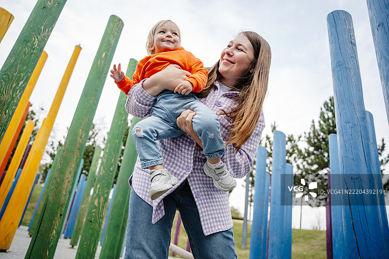 母亲在五彩斑斓的游乐场抱着女儿图片素材