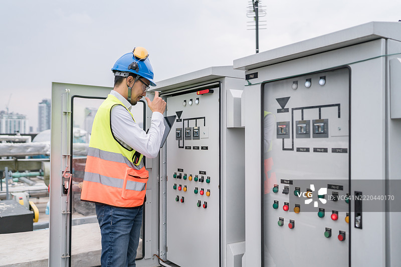 电气工程师在屋顶检查电源控制面板或配电盘图片素材