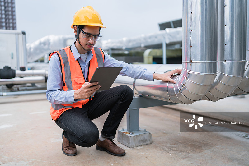技术人员在工厂检查工业管道时使用平板电脑进行诊断图片素材