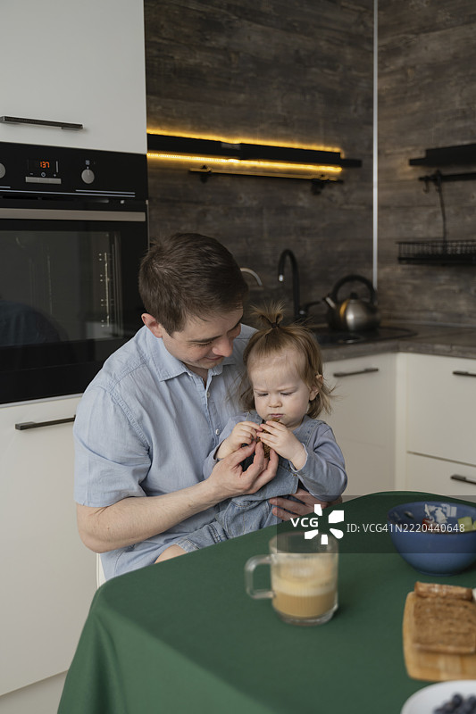 父亲和女儿在厨房餐桌上享受早餐的亲密时光图片素材