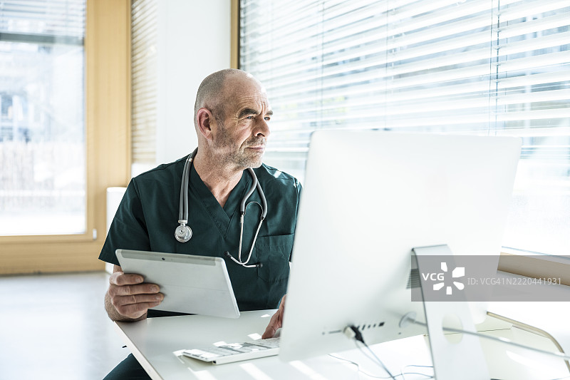 医生在诊所办公室使用平板电脑和电脑进行研究图片素材