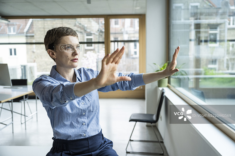 办公室里的女性佩戴增强现实眼镜进行未来工作互动图片素材