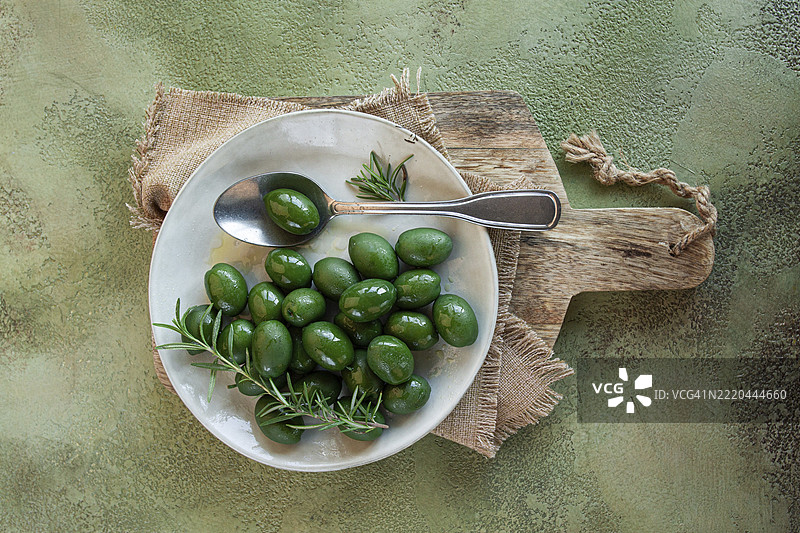 查尔基迪基橄榄，经典希腊绿橄榄，放在盘子里，配有一把勺子，俯视图，无人。图片素材