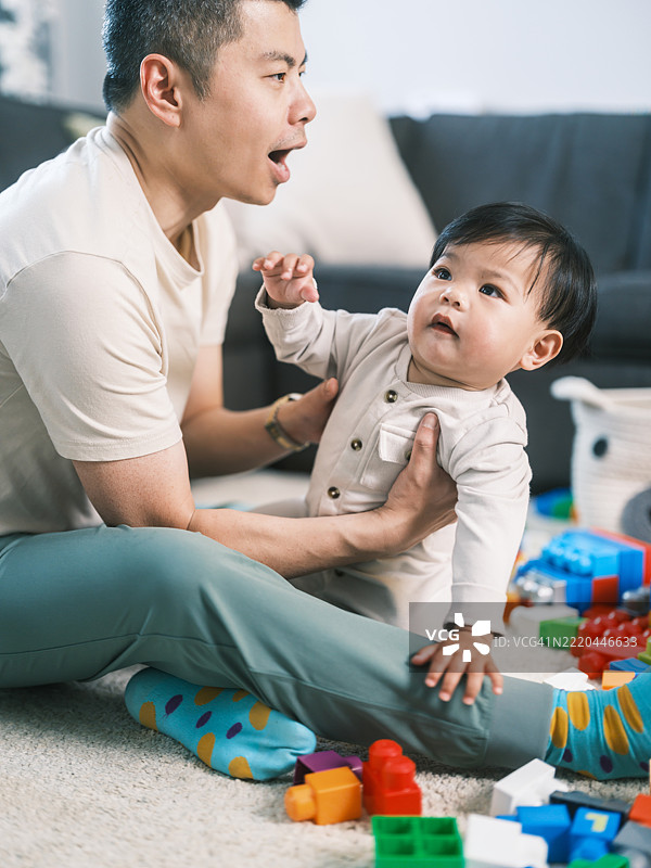 年轻的韩国父亲在家与幼儿儿子玩耍图片素材