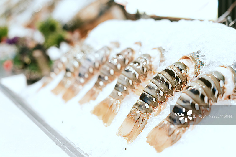 新鲜龙虾尾在海鲜市场展示的冰上排列图片素材