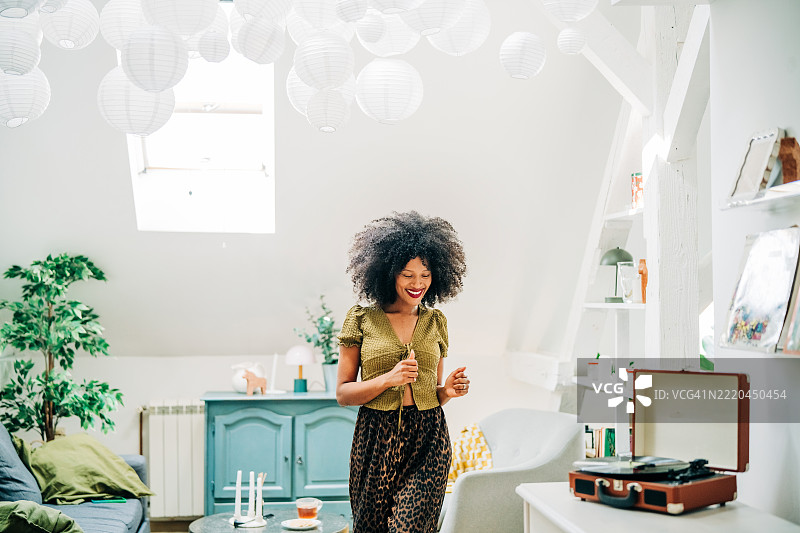 年轻女性在家中听着唱片机跳舞。图片素材