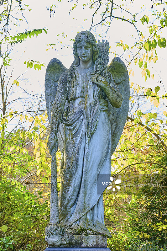 秋天的环境中，一位石制天使手持剑，周围是五彩斑斓的树叶，墓地，德国巴登-符腾堡州曼海姆，欧洲图片素材