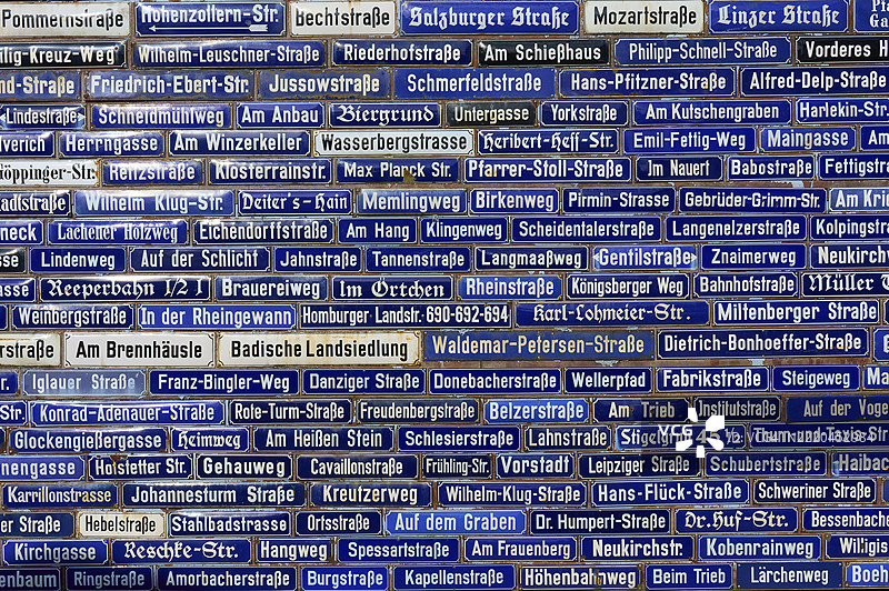 许多蓝色路牌的墙壁，上面显示着不同的地名，如阿莫尔巴赫、奥登瓦尔德、巴伐利亚、德国、欧洲。图片素材