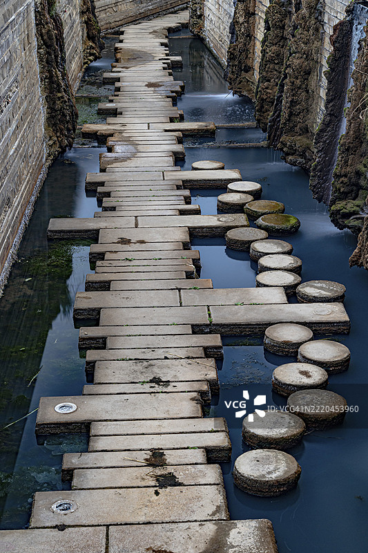 石头台阶和混凝土块沿着狭窄的水道延伸，位于德国萨尔州兰茨维勒-雷登的水景花园。图片素材