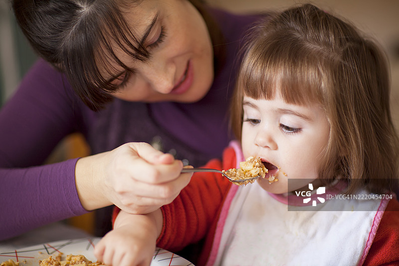 母亲在早晨家中喂小女儿吃早餐图片素材