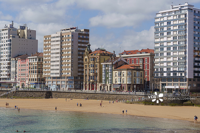 西班牙阿斯图里亚斯市吉洪的海滩景观，背景是城市天际线和海岸边的摩天大楼图片素材