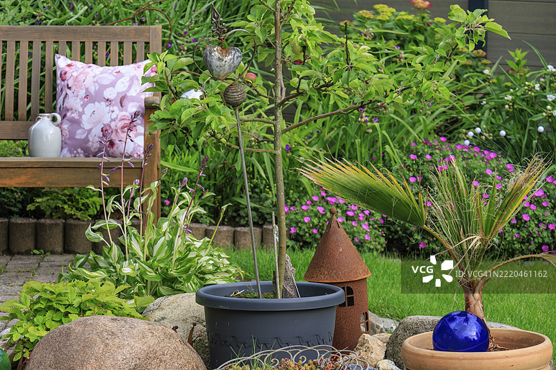 一个小花园区域，里面有花朵、长椅和装饰元素，位于德国明斯特地区的比勒尔贝克。图片素材