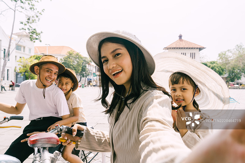 美丽的亚洲四口之家在雅加达的古城骑自行车自拍图片素材