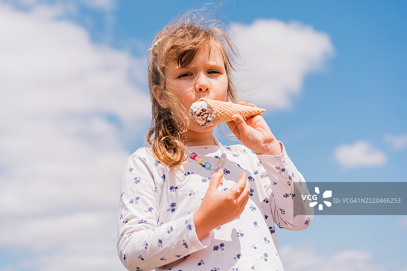女孩在夏天的蓝天下户外吃冰淇淋图片素材