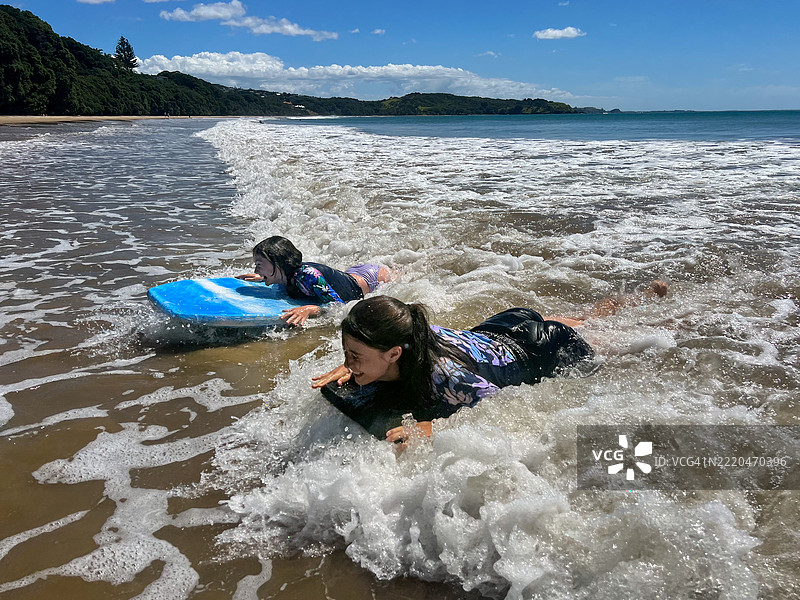 两个女孩在海里一起冲浪滑板图片素材